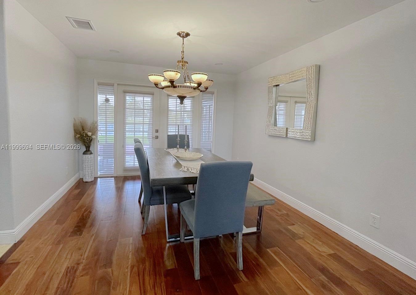 A dining room features a wooden table, blue upholstered chairs, and a chandelier — 18281 SW 22nd St, Miramar FL 33029, MIRAMAR, FL
