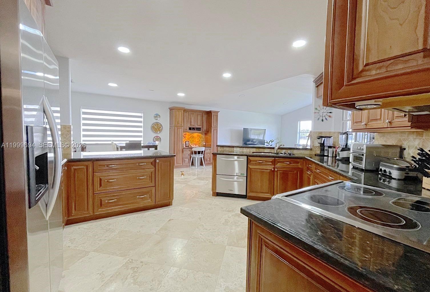 A kitchen features wood cabinets, dark countertops, stainless steel appliances, and light-colored tile flooring — 18281 SW 22nd St, Miramar FL 33029, MIRAMAR, FL