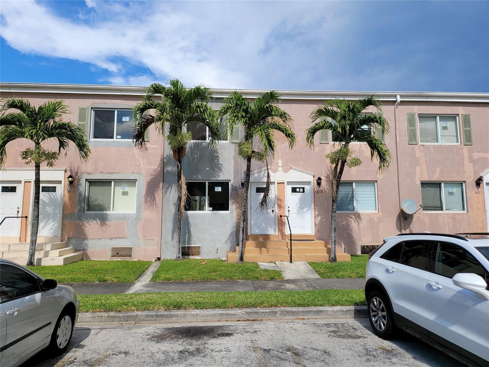 A two-story townhouse exterior features pink and gray stucco walls with three palm trees — 8451 NW 4th Avenue # 8451, Miami FL 33150, MIAMI, FL
