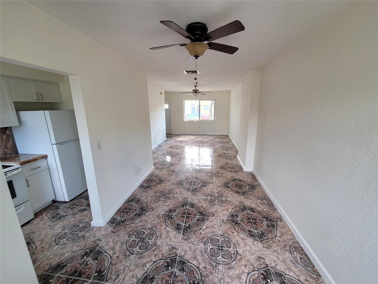 A long, narrow room with patterned tile flooring, white walls, and two ceiling fans — 8451 NW 4th Avenue # 8451, Miami FL 33150, MIAMI, FL