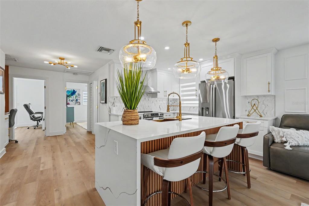A modern kitchen features a white marble island with bar stools and gold pendant lighting — 1927 SHORE ACRES BOULEVARD NE, ST PETERSBURG, FL
