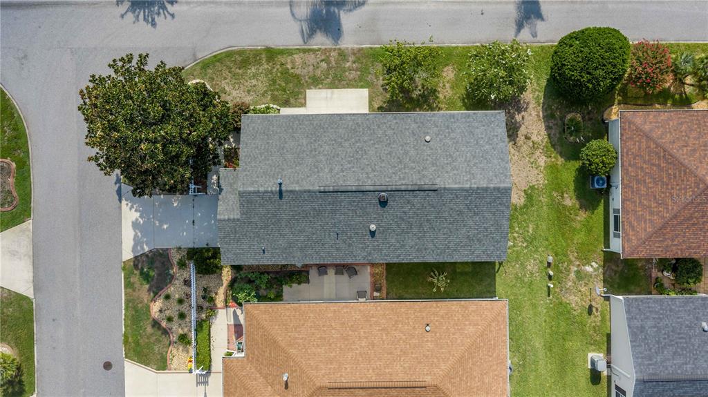 An aerial view shows the gray shingled roof of a house surrounded by green lawns — 272 EMMALEE PLACE, THE VILLAGES, FL
