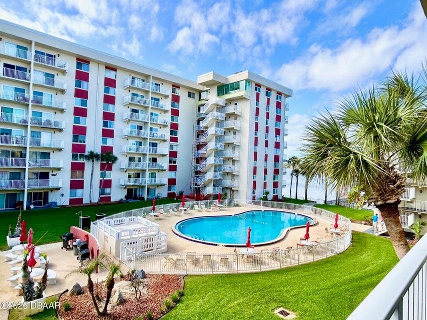 An exterior view of a multi-story apartment building with a swimming pool and palm trees — 2711 N HALIFAX AVENUE UNIT 374, DAYTONA BEACH, FL