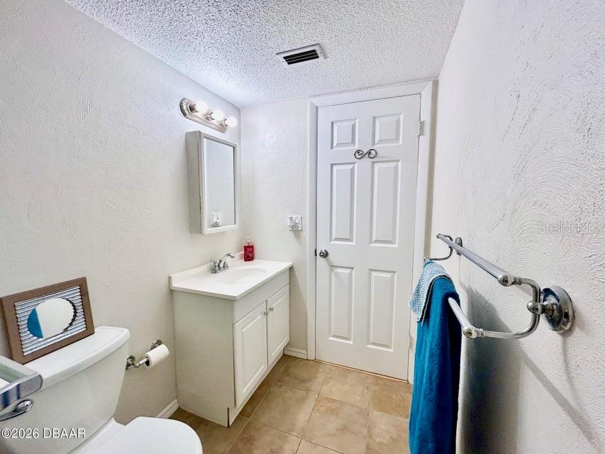 A bathroom features a white vanity, a toilet, a towel rack, and a closed door — 2711 N HALIFAX AVENUE UNIT 374, DAYTONA BEACH, FL