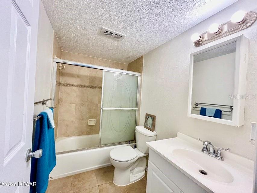 This bathroom features a white vanity, a toilet, and a shower-tub combo with tiled walls — 2711 N HALIFAX AVENUE UNIT 374, DAYTONA BEACH, FL