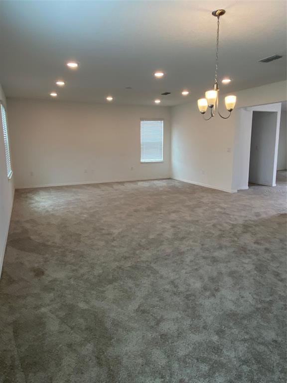 An empty room with gray carpeting, recessed lighting, a chandelier, and a window — 999 CUMBERLAND DRIVE, POINCIANA, FL
