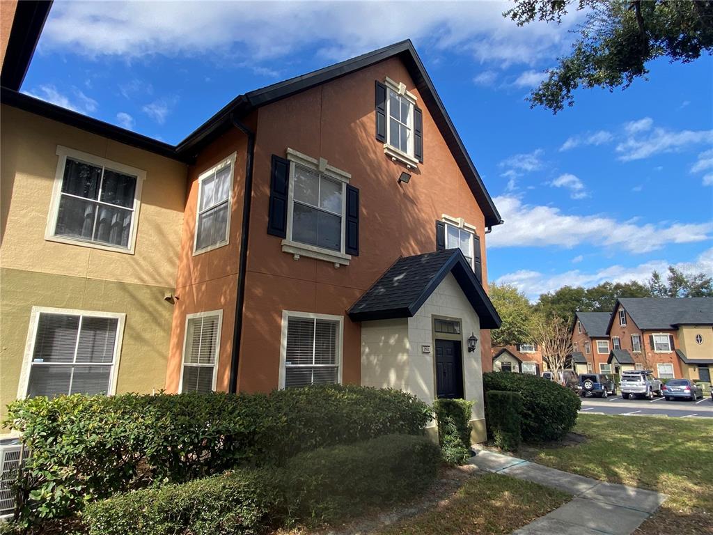 A two-story townhouse with a brown stucco exterior, black shutters, and a small covered entryway — 6025 WESTGATE DRIVE UNIT 2512, ORLANDO, FL