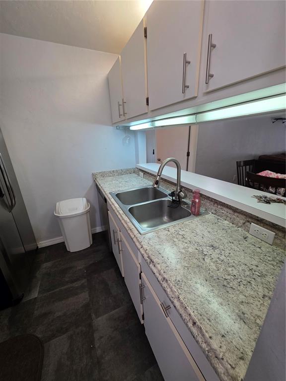 A kitchen features light-colored cabinets, granite countertops, a stainless steel sink, and dark flooring — 4000 SW 23RD STREET UNIT 6-305, GAINESVILLE, FL