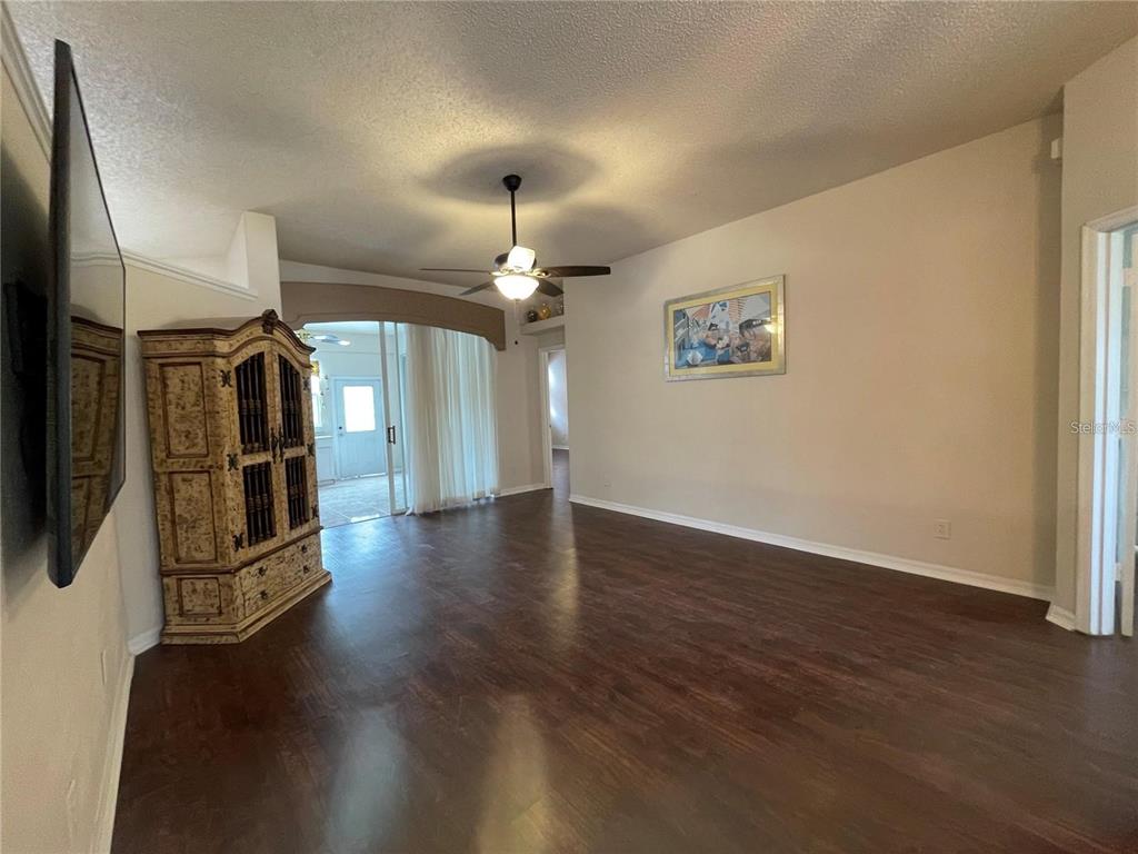 A living room features dark wood flooring, a ceiling fan, and a decorative armoire — 1924 RACHELS RIDGE LOOP, OCOEE, FL