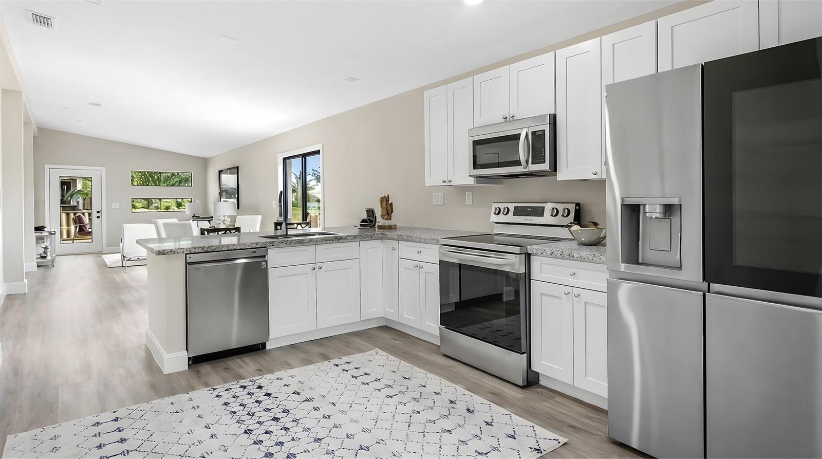 A modern kitchen features white cabinets, stainless steel appliances, and granite countertops — 8019 NW 8th Avenue, Miami FL 33150, MIAMI, FL