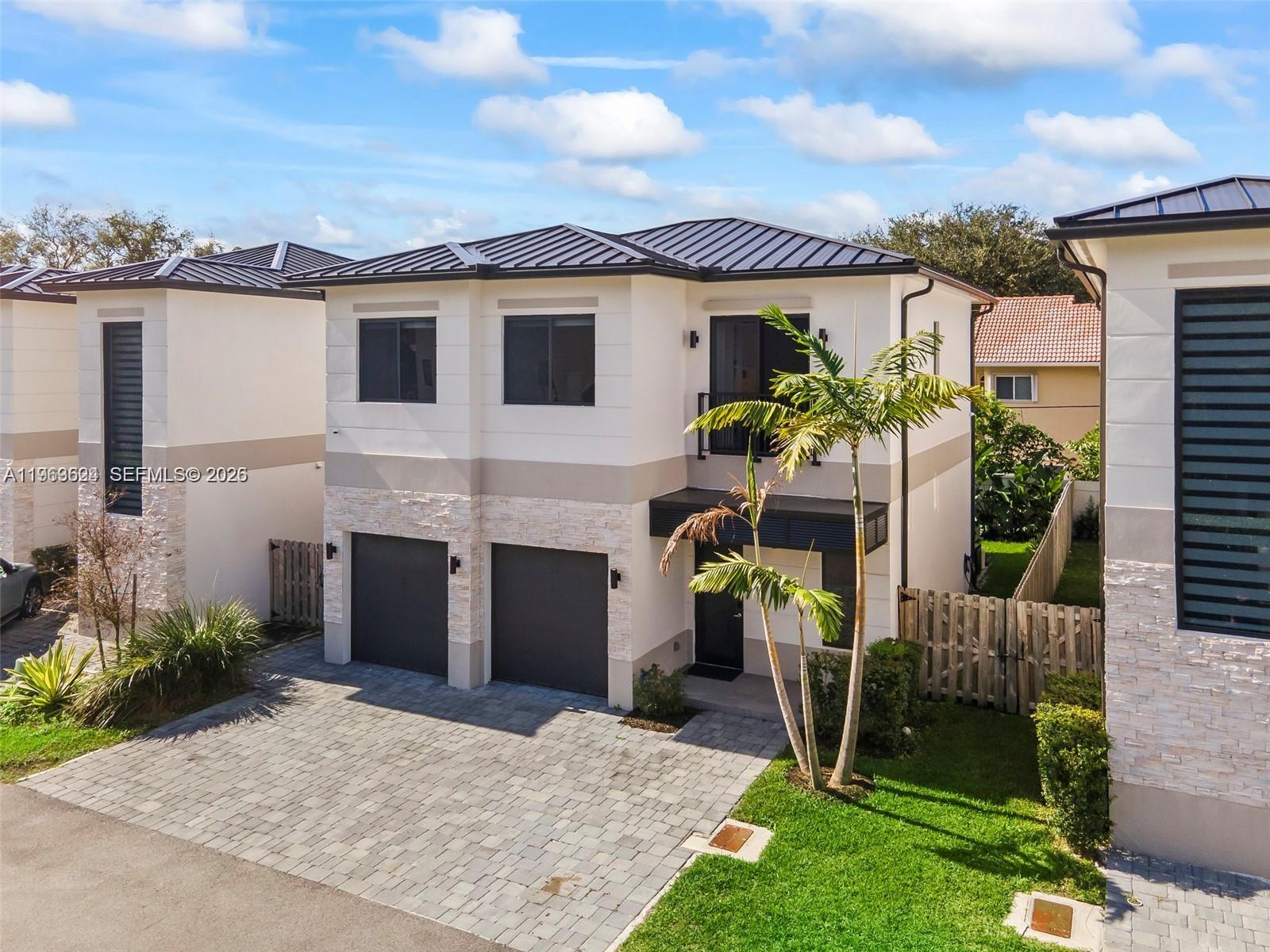A two-story house features a paved driveway, two garage doors, and a palm tree — 7771 SW 99th St, Miami FL 33156, MIAMI, FL