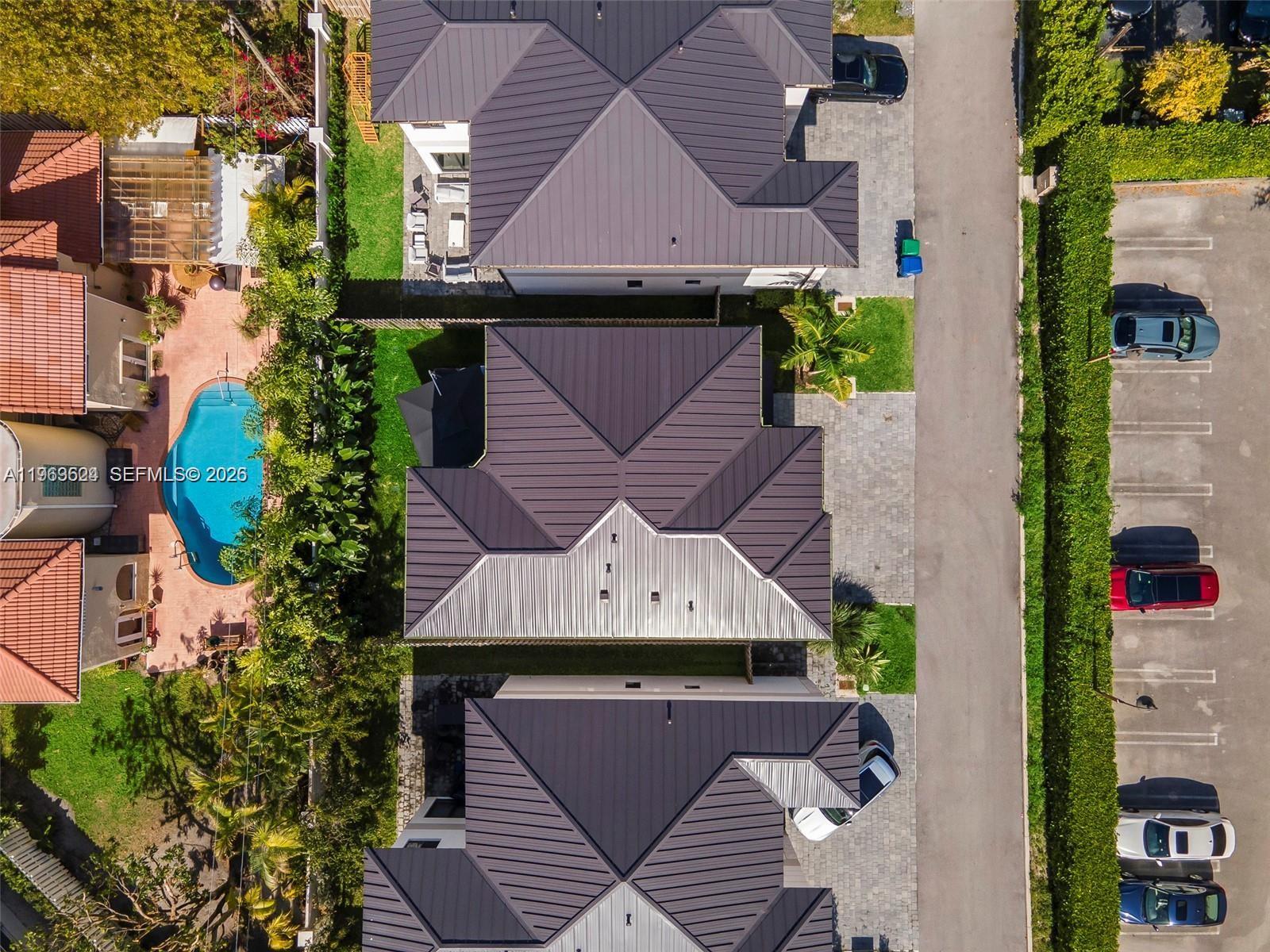 An aerial view shows several houses with dark metal roofs, a swimming pool, and parking — 7771 SW 99th St, Miami FL 33156, MIAMI, FL