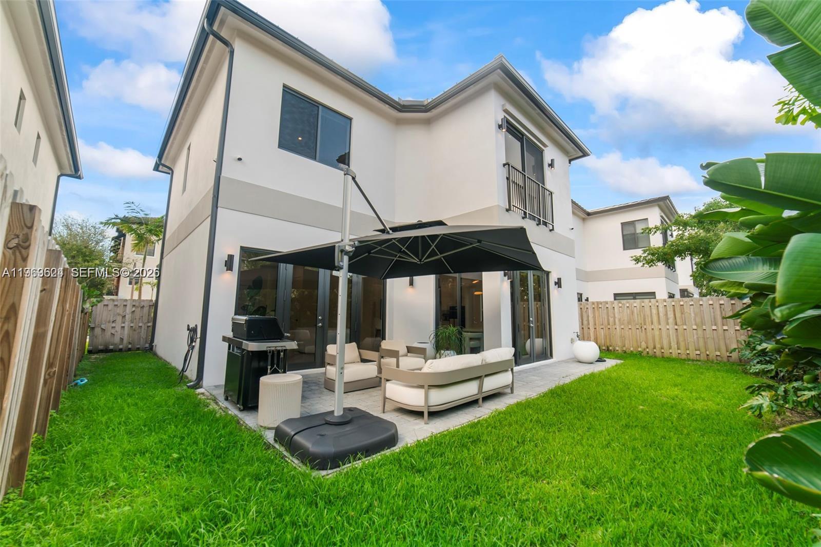 The backyard features a paved patio with outdoor furniture, a grill, and a large umbrella — 7771 SW 99th St, Miami FL 33156, MIAMI, FL
