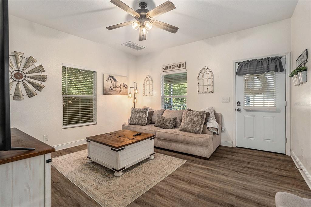 A living room features a beige sofa, a wooden coffee table, and farmhouse-style wall decor — 4921 6TH STREET, ZEPHYRHILLS, FL