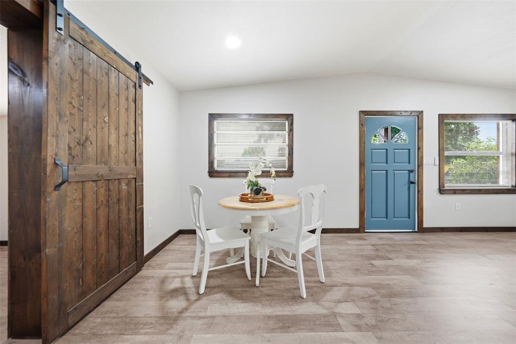 A dining area features a small round table, white chairs, wood-look flooring, and a blue door — 906 SABRINA DRIVE, OCOEE, FL