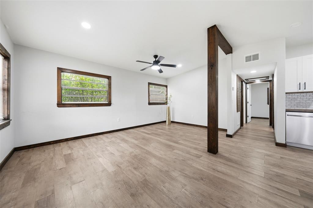 A living area with light wood flooring, white walls, dark wood trim, and a support beam — 906 SABRINA DRIVE, OCOEE, FL