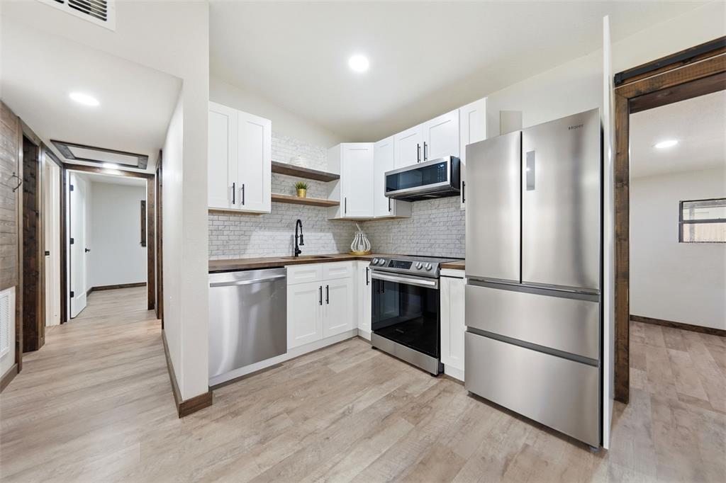 A kitchen features white cabinets, stainless steel appliances, wood countertops, and a subway tile backsplash — 906 SABRINA DRIVE, OCOEE, FL