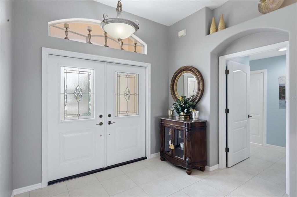 A bright entryway features double front doors, a decorative arched transom window, and tile flooring — 82 PINEHURST PLACE, ROTONDA WEST, FL