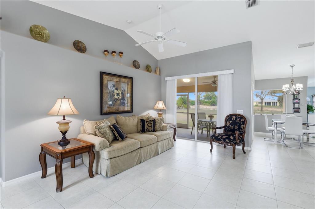 A living room with a beige sofa, tiled floors, and a sliding glass door — 82 PINEHURST PLACE, ROTONDA WEST, FL