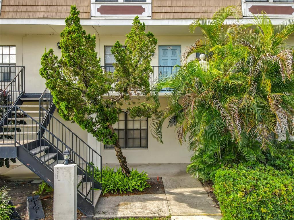An exterior view of a two-story townhouse with a metal staircase and a palm tree — 6034 VILLAGE CIRCLE UNIT GE, ORLANDO, FL