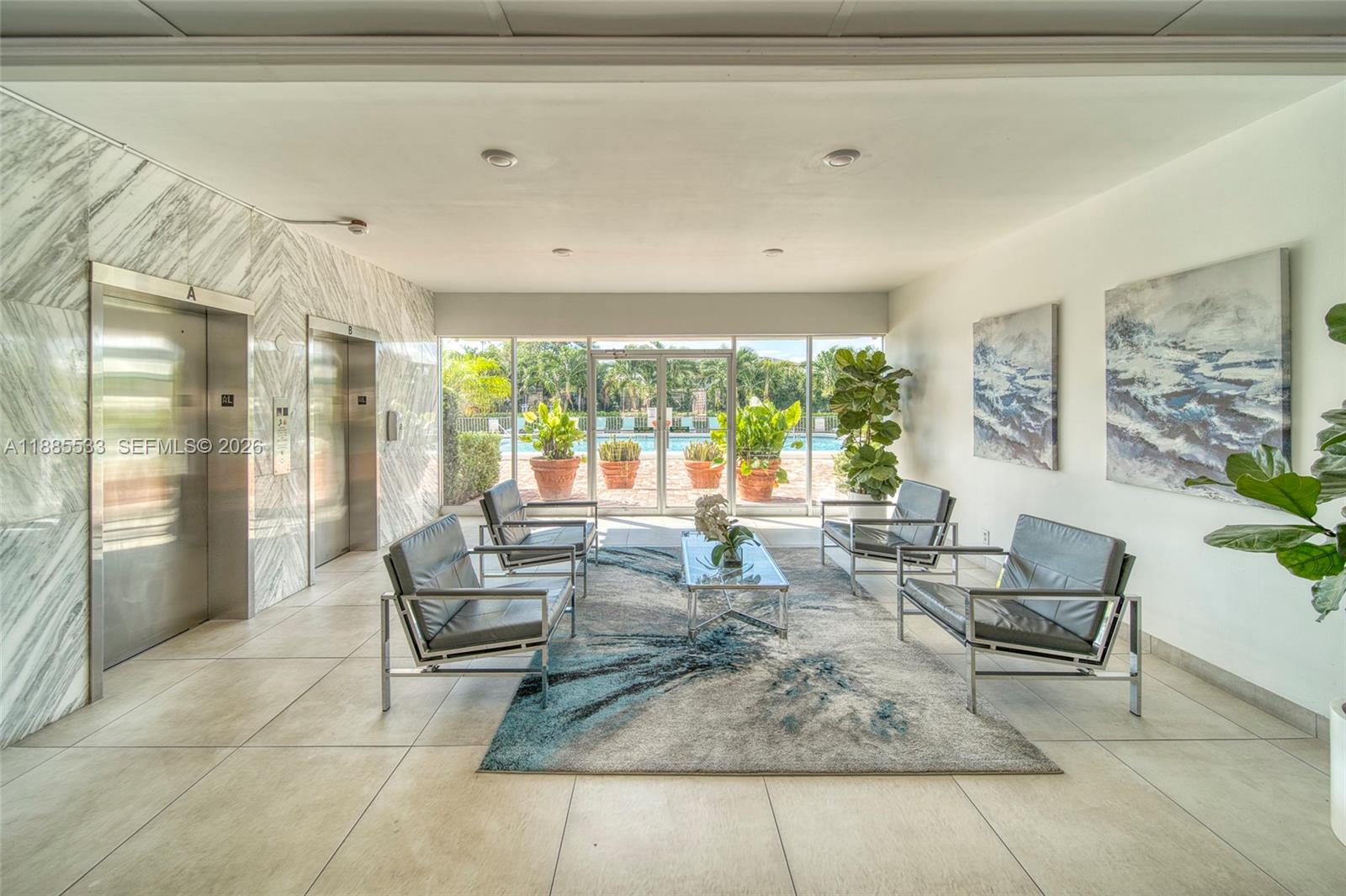 A modern lobby features four leather chairs, a glass coffee table, and two metal elevators — 401 Golden Isles Dr # 908, Hallandale Beach FL 33009, HALLANDALE BEACH, FL