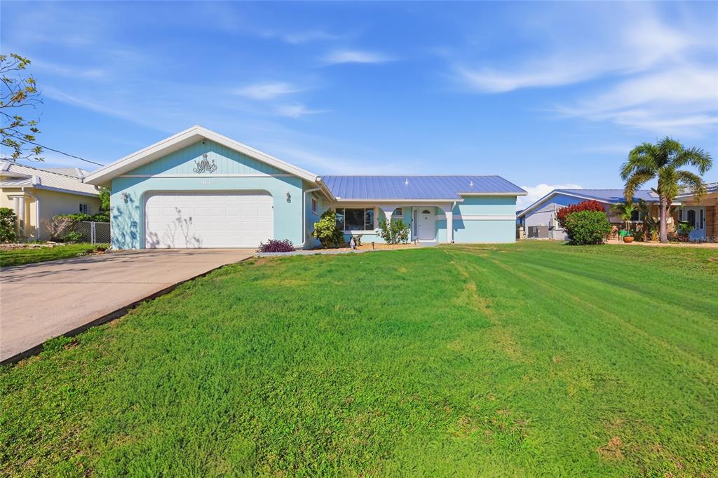 A light blue single-story house with a metal roof and a two-car garage — 414 SPRING LAKE BOULEVARD NW, PORT CHARLOTTE, FL
