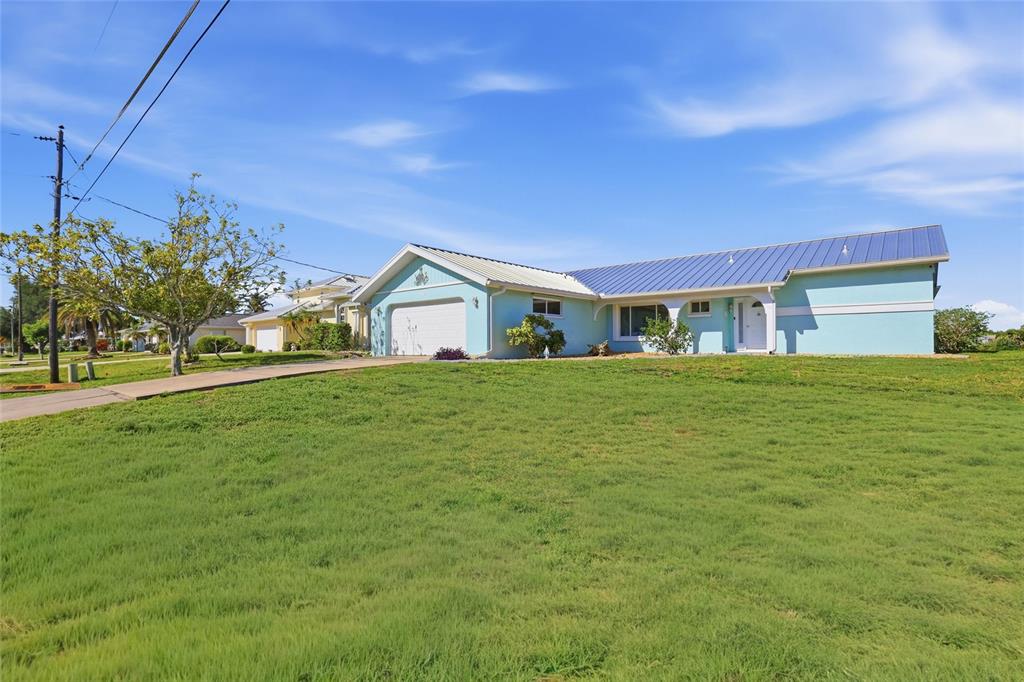 A light blue single-story house with a metal roof and a large front lawn — 414 SPRING LAKE BOULEVARD NW, PORT CHARLOTTE, FL
