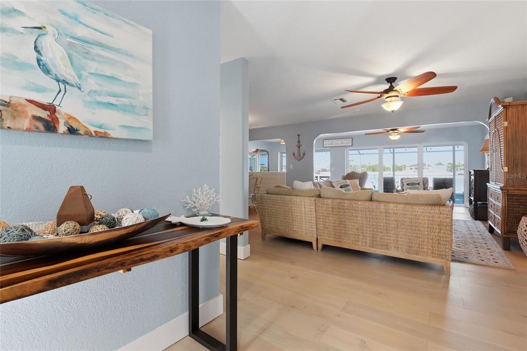 A light blue entryway leads into a living room with wicker furniture and wood flooring — 414 SPRING LAKE BOULEVARD NW, PORT CHARLOTTE, FL