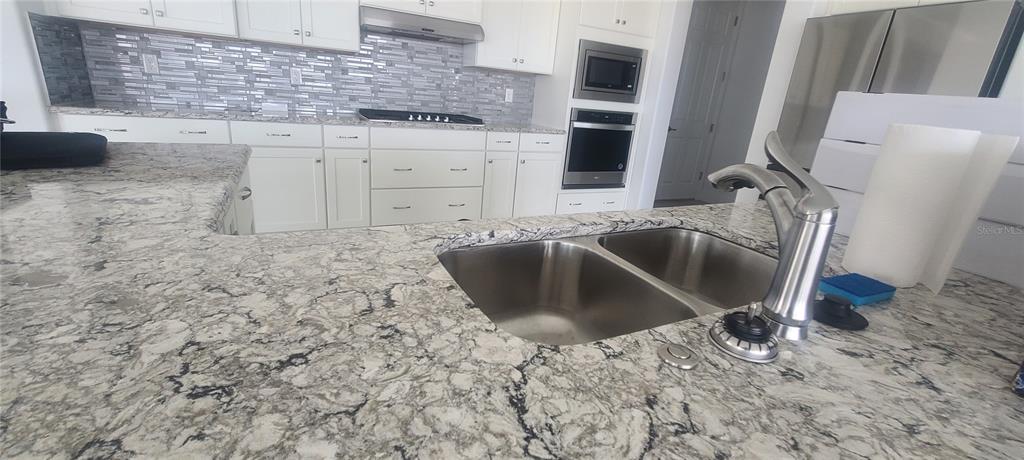 A kitchen features white cabinets, granite countertops, a double sink, and stainless steel appliances — 9754 SW 103RD AVENUE, OCALA, FL