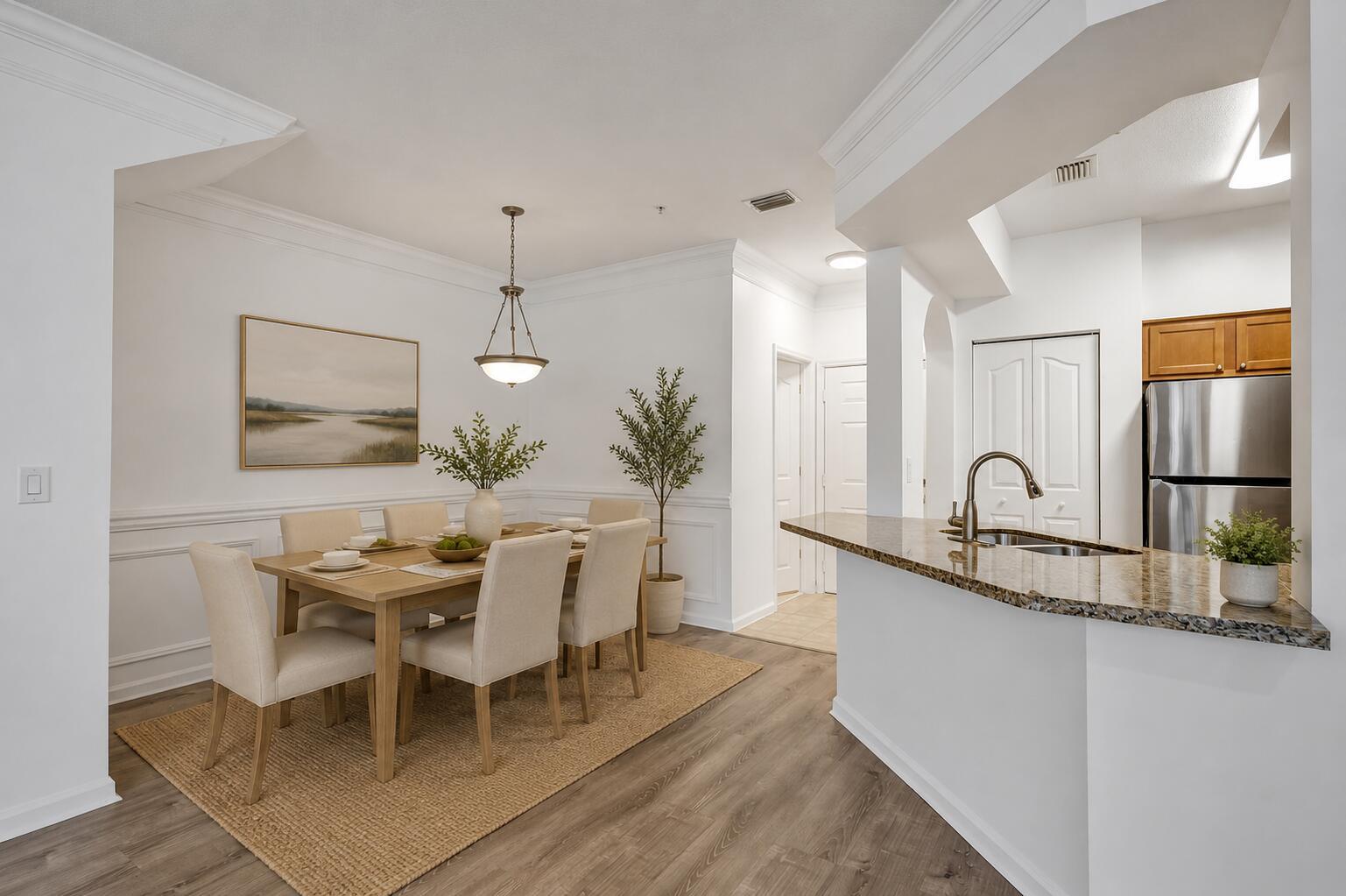 A dining area with a wooden table and chairs sits beside a kitchen breakfast bar — 826 Dakota Drive # 102, Jupiter FL 33458, JUPITER, FL