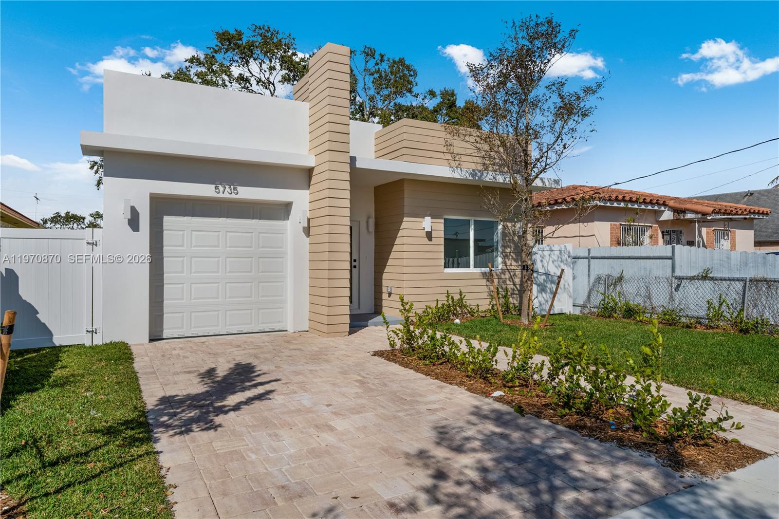 A modern single-story house features a white garage, tan horizontal siding, and a paved driveway — 5735 SW 4th St, Miami FL 33144, MIAMI, FL