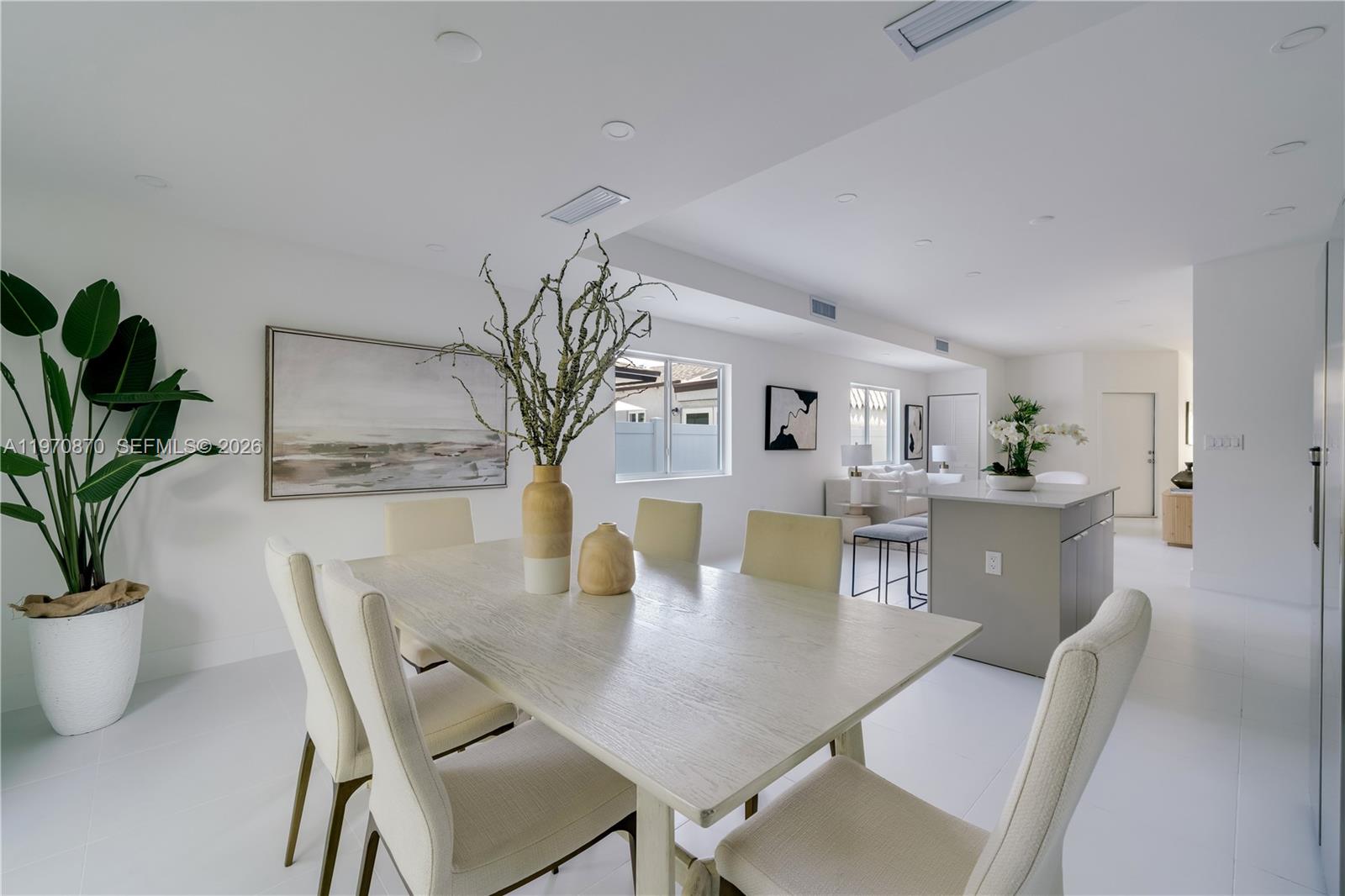 A bright dining area features a light wood table, upholstered chairs, and a large plant — 5735 SW 4th St, Miami FL 33144, MIAMI, FL