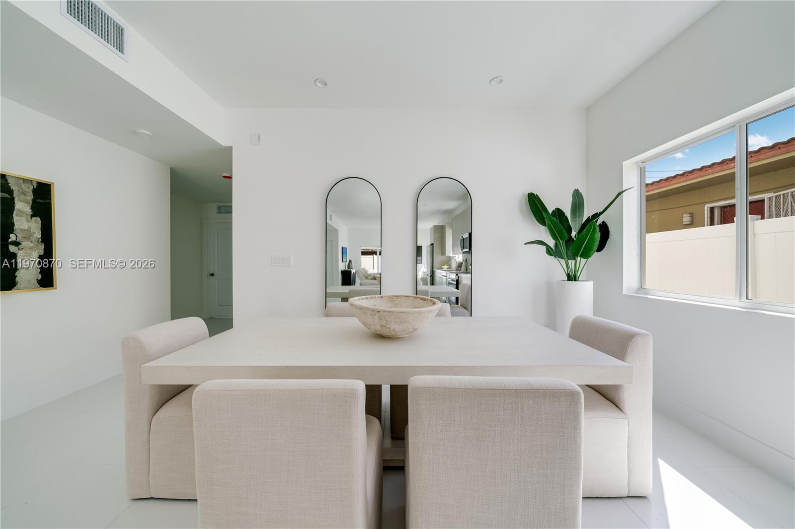 A dining room features a square table, upholstered chairs, two arched mirrors, and a large plant — 5735 SW 4th St, Miami FL 33144, MIAMI, FL