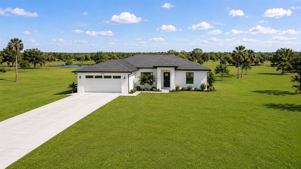 A white single-story house with a dark roof sits on a large, grassy rural lot — 7042 GROVE BOULEVARD, PUNTA GORDA, FL