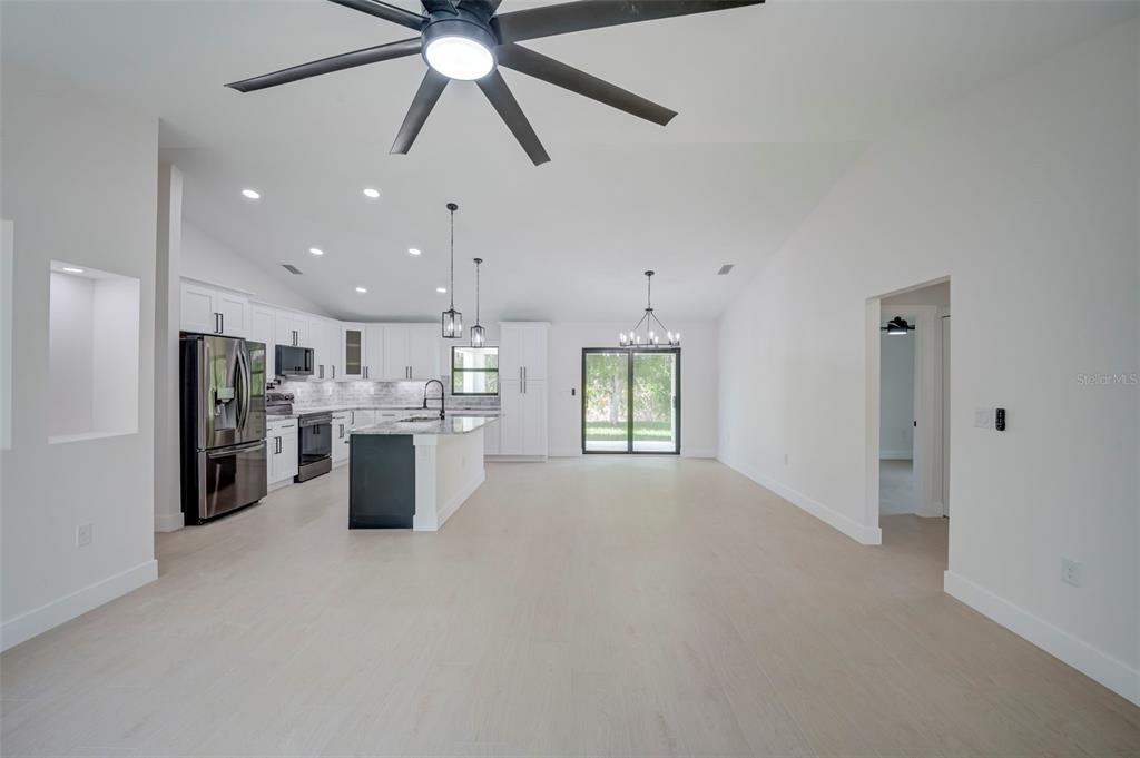 A modern open-concept kitchen and living area features white cabinetry, a dark island, and flooring — 7042 GROVE BOULEVARD, PUNTA GORDA, FL