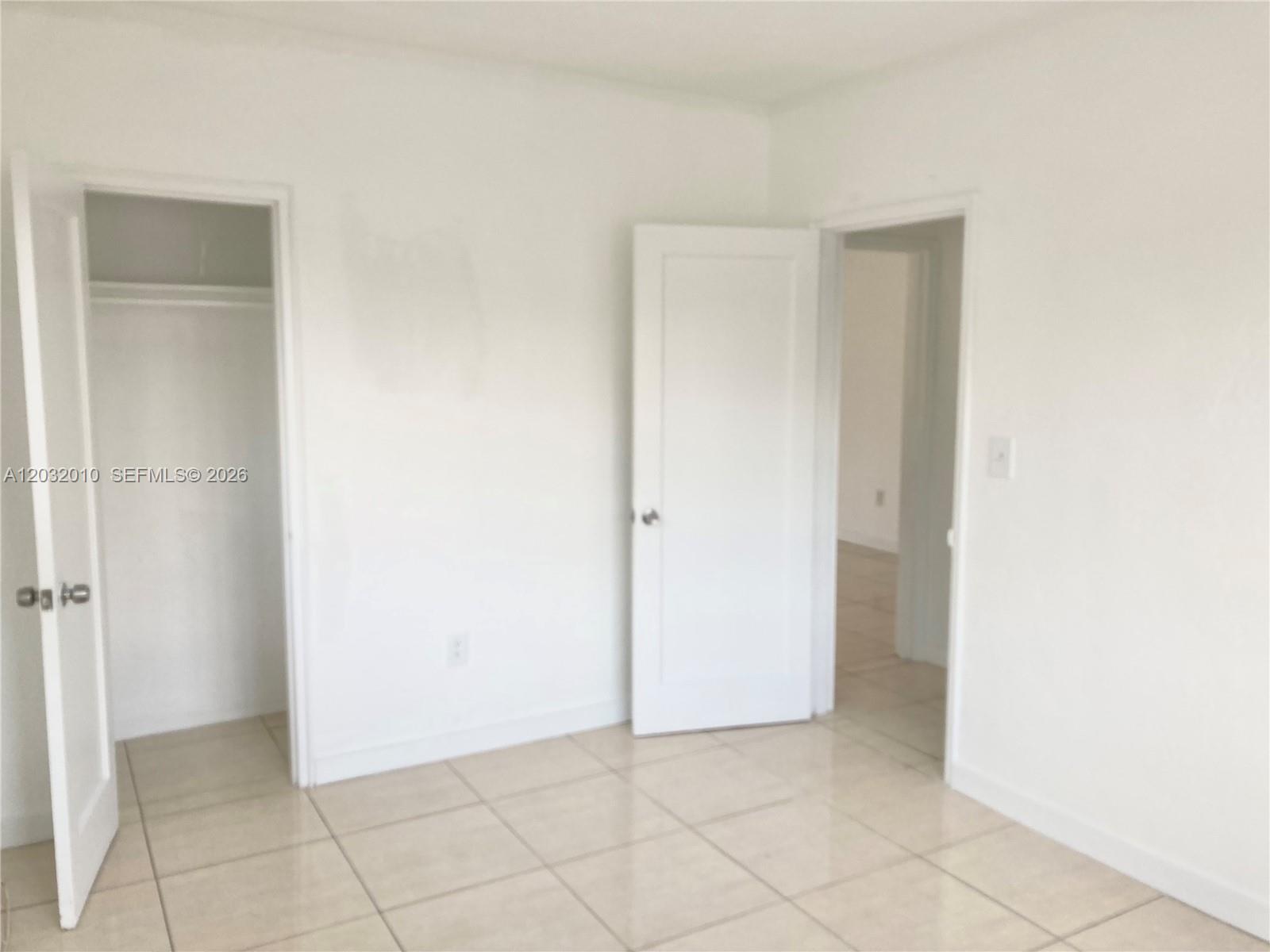 An empty room features white walls, light-colored tile flooring, and two open doorways — 625 83rd St # 44, Miami Beach FL 33141, MIAMI BEACH, FL