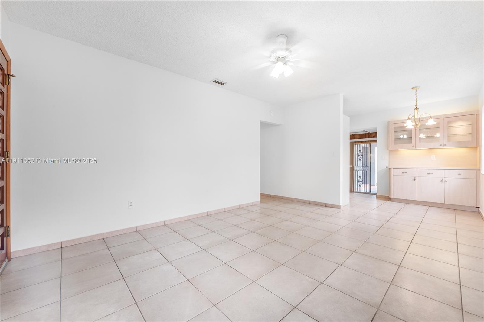 An open-concept room features white walls, light-colored tile flooring, a ceiling fan, and cabinetry — 682 W 37th St, Hialeah FL 33012, HIALEAH, FL