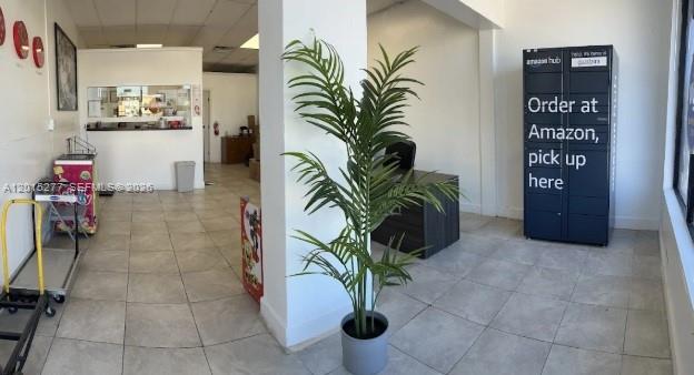 A commercial interior features a tiled floor, a potted palm plant, and an Amazon locker — Established Pack, Ship, Mailbox & Business Service, Hollywood FL 33021, HOLLYWOOD, FL