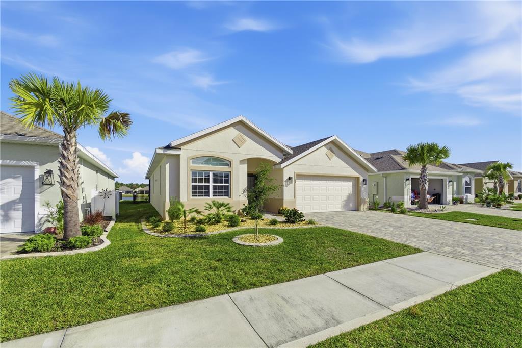 A single-story suburban house with a paved driveway, palm trees, and a grassy front yard — 14 MATANZAS LAKES DRIVE, PALM COAST, FL