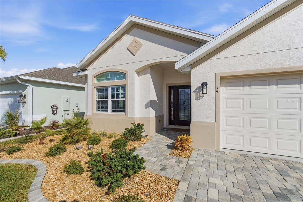 A single-story house exterior features a paved walkway, a garage, and a landscaped front yard — 14 MATANZAS LAKES DRIVE, PALM COAST, FL