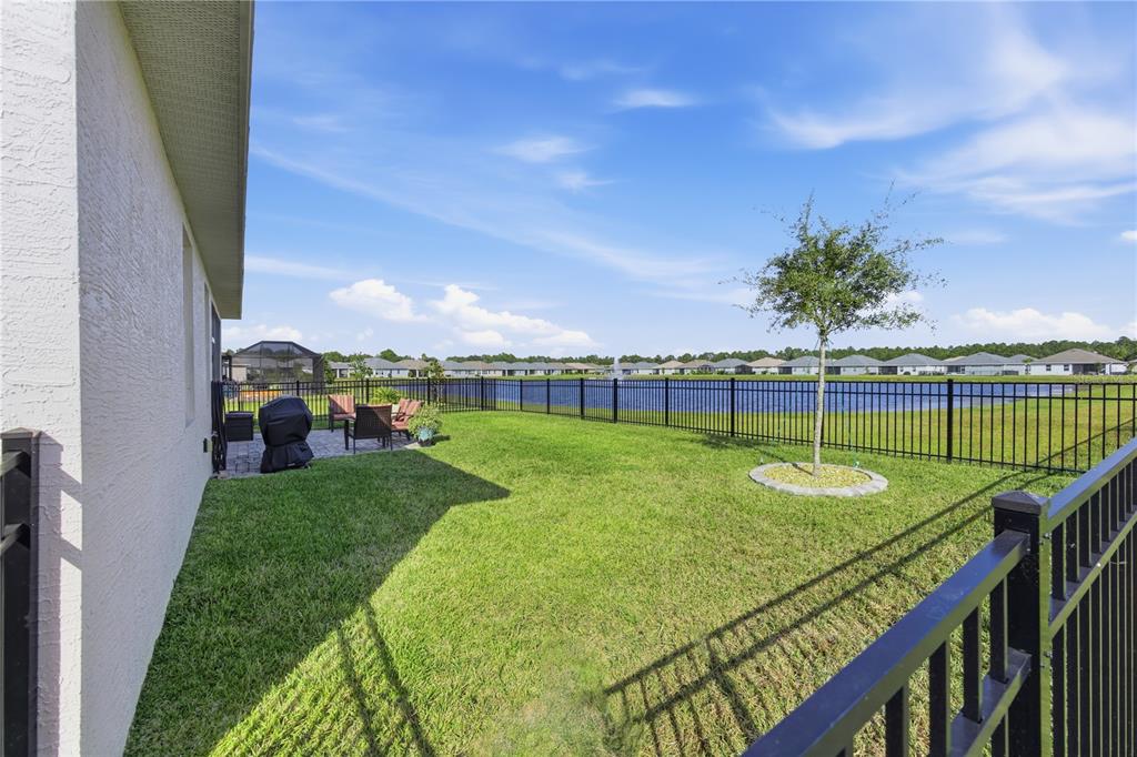 A backyard with a patio, a small tree, and a black fence overlooking a lake — 14 MATANZAS LAKES DRIVE, PALM COAST, FL