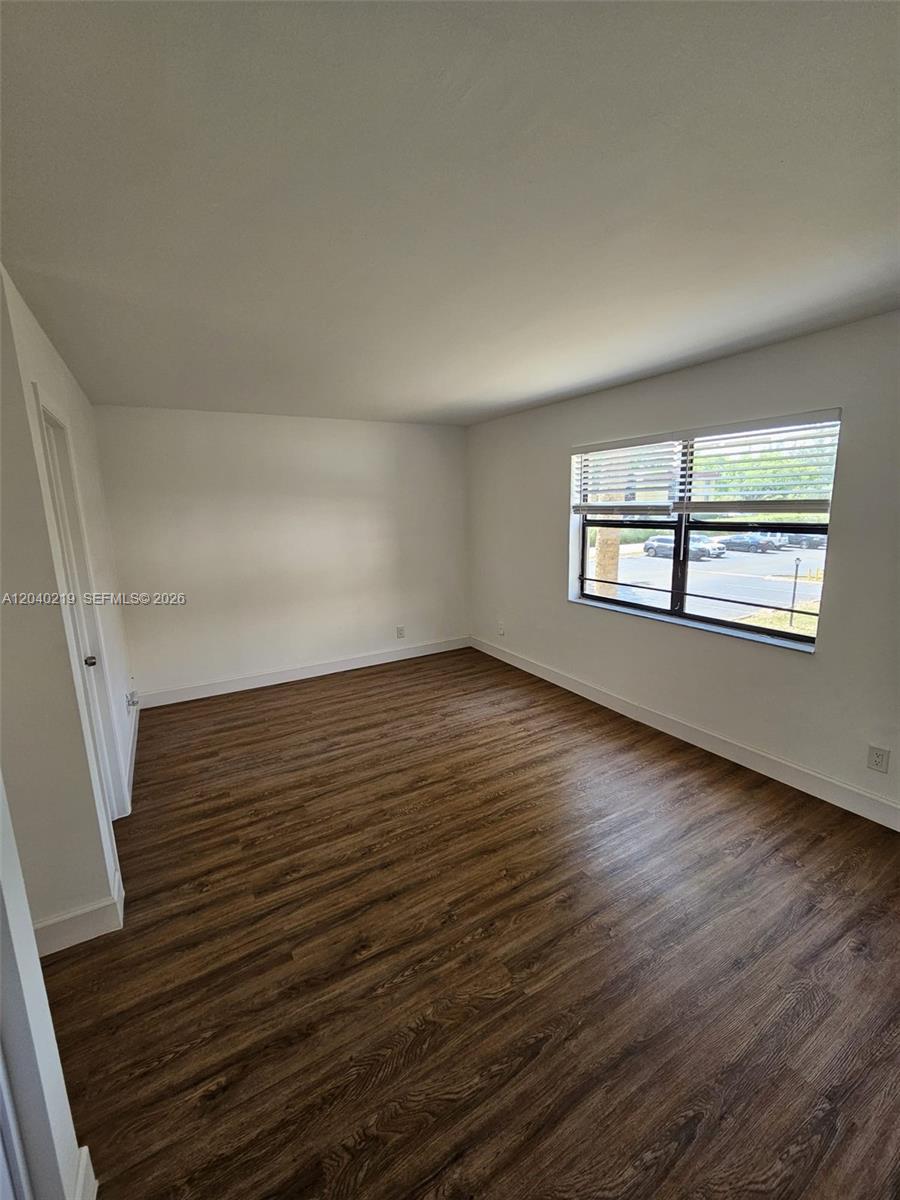 An empty room features wood-look flooring, white walls, and a window with horizontal blinds — 3252 Foxcroft Rd # 216, Miramar FL 33025, MIRAMAR, FL