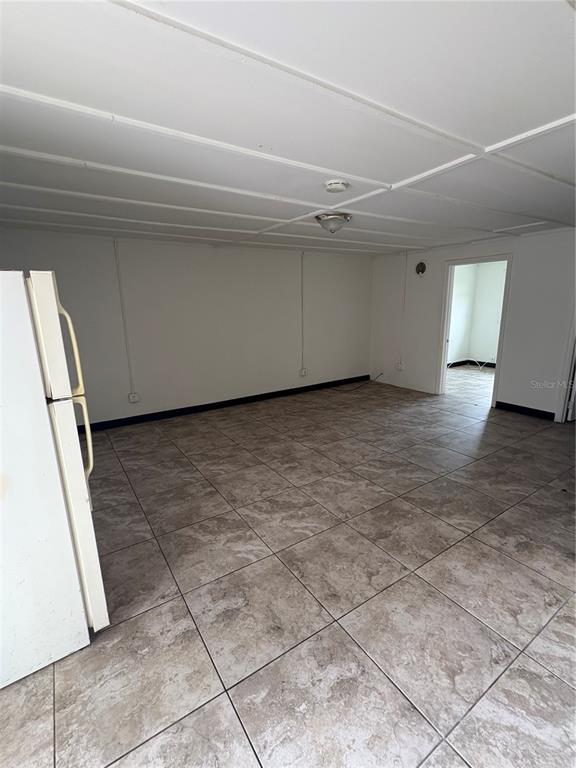 An empty room with tiled floors, a white drop ceiling, and a white refrigerator — 14846 17TH STREET, DADE CITY, FL