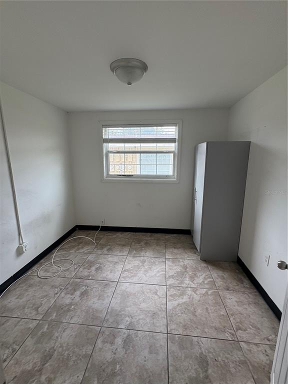 A small, empty room features white walls, tiled flooring, a single window, and a gray cabinet — 14846 17TH STREET, DADE CITY, FL