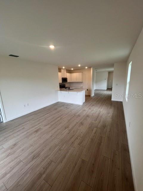 An open-concept kitchen with white cabinets and a center island overlooks a spacious living area — 1365 CAMELLIA BLOOM LANE, SANFORD, FL