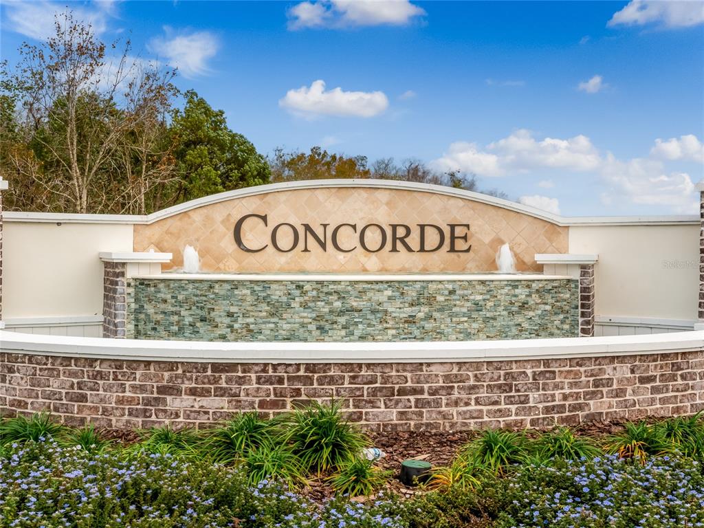 A stone and brick monument sign for Concorde features a water fountain and landscaping — 1365 CAMELLIA BLOOM LANE, SANFORD, FL