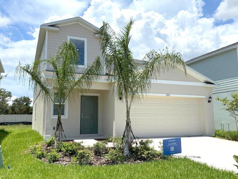 A two-story suburban house features a beige exterior, a two-car garage, and two palm trees — 11913 NOBLE CHASE PATH, DADE CITY, FL