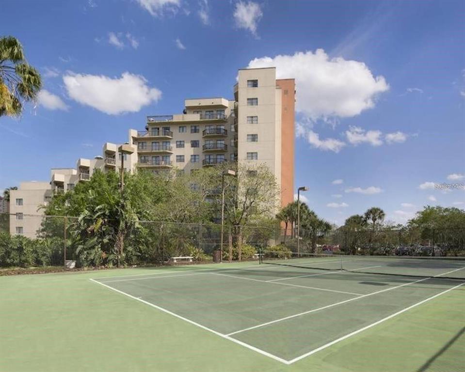 A tennis court sits in the foreground with a multi-story apartment building in the background — 6165 CARRIER DRIVE UNIT 2103, ORLANDO, FL