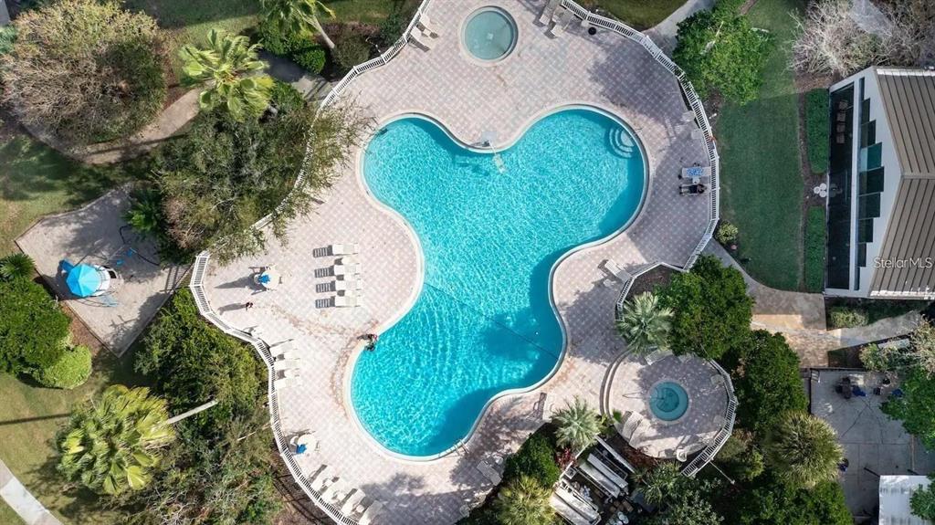 An aerial view shows a clover-shaped swimming pool with two attached hot tubs and surrounding patio — 6165 CARRIER DRIVE UNIT 2103, ORLANDO, FL