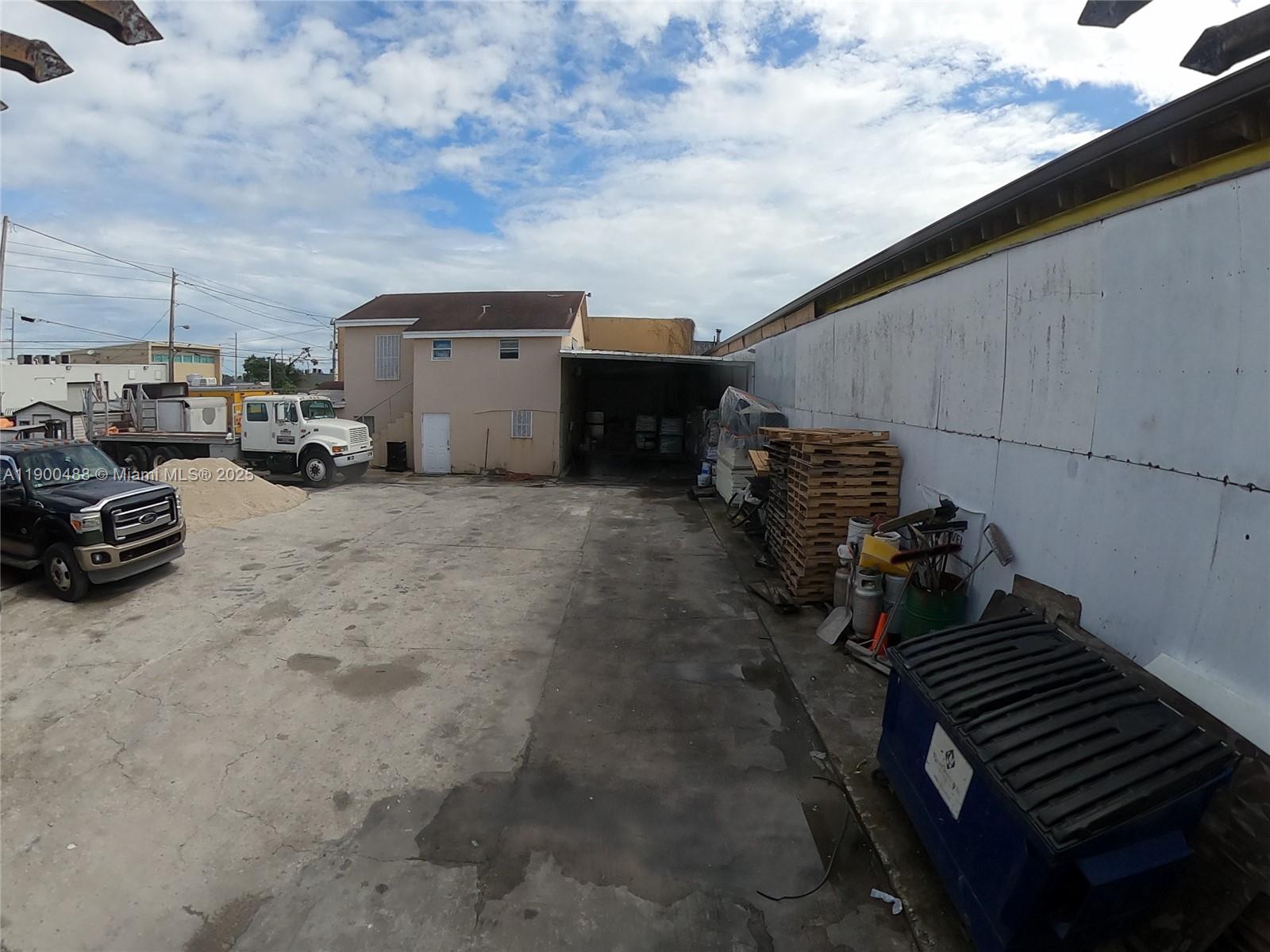 An exterior view shows a concrete lot with a truck, pallets, and a dumpster — 2484 NW 21st Ter, Miami FL 33142, MIAMI, FL
